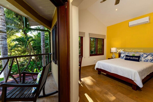 A bedroom with a bed, a window, and a balcony with a chair.