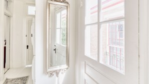 A hallway with a large ornate mirror, a white door, and a window with a view of a brick building. - HISTORIC HOME - Walk to French Quarter - Free Parking - Sleeps 10 (New Orleans)