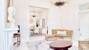 A spacious living room with a round coffee table, a beige sofa, and a chandelier. - HISTORIC HOME - Walk to French Quarter - Free Parking - Sleeps 10 (New Orleans)