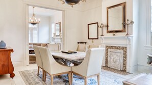 A dining room with a marble table, white chairs, a chandelier, a fireplace, and a large mirror. - HISTORIC HOME - Walk to French Quarter - Free Parking - Sleeps 10 (New Orleans)