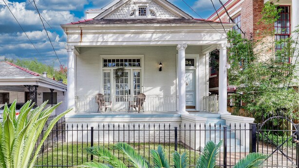 A white colonial-style house with a front porch, a brick chimney, and a number 34 on the door. - HISTORIC HOME - Walk to French Quarter - Free Parking - Sleeps 10 (New Orleans)