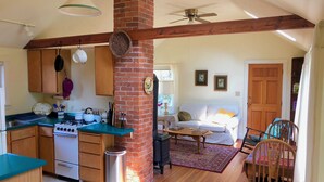 A spacious kitchen with wooden cabinets, a gas stove, and a brick chimney. - Garden Cottage on College Hill (Eugene)