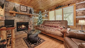 A cozy living room with a stone fireplace, a Christmas tree, and a leather sofa. - Matthew11:28~4 mil Pkwy-Dwntwn Pigfrge hot tub, wifi-gas fireplace-NO EXTRA FEES (Pigeon Forge)