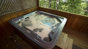 Ein Whirlpool mit einer Holterrasse und Blick auf Bäume.