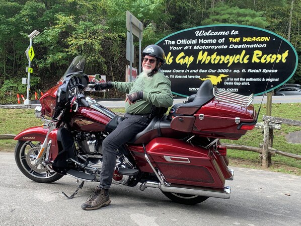 Une personne est assise sur une moto Harley-Davidson devant un panneau indiquant l'entrée du complexe hôtelier Gap Motorcycle Resort.