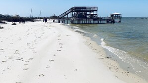 Ein Strand mit einer Seebrücke, die ins Wasser führt, und einer überdachten Konstruktion.