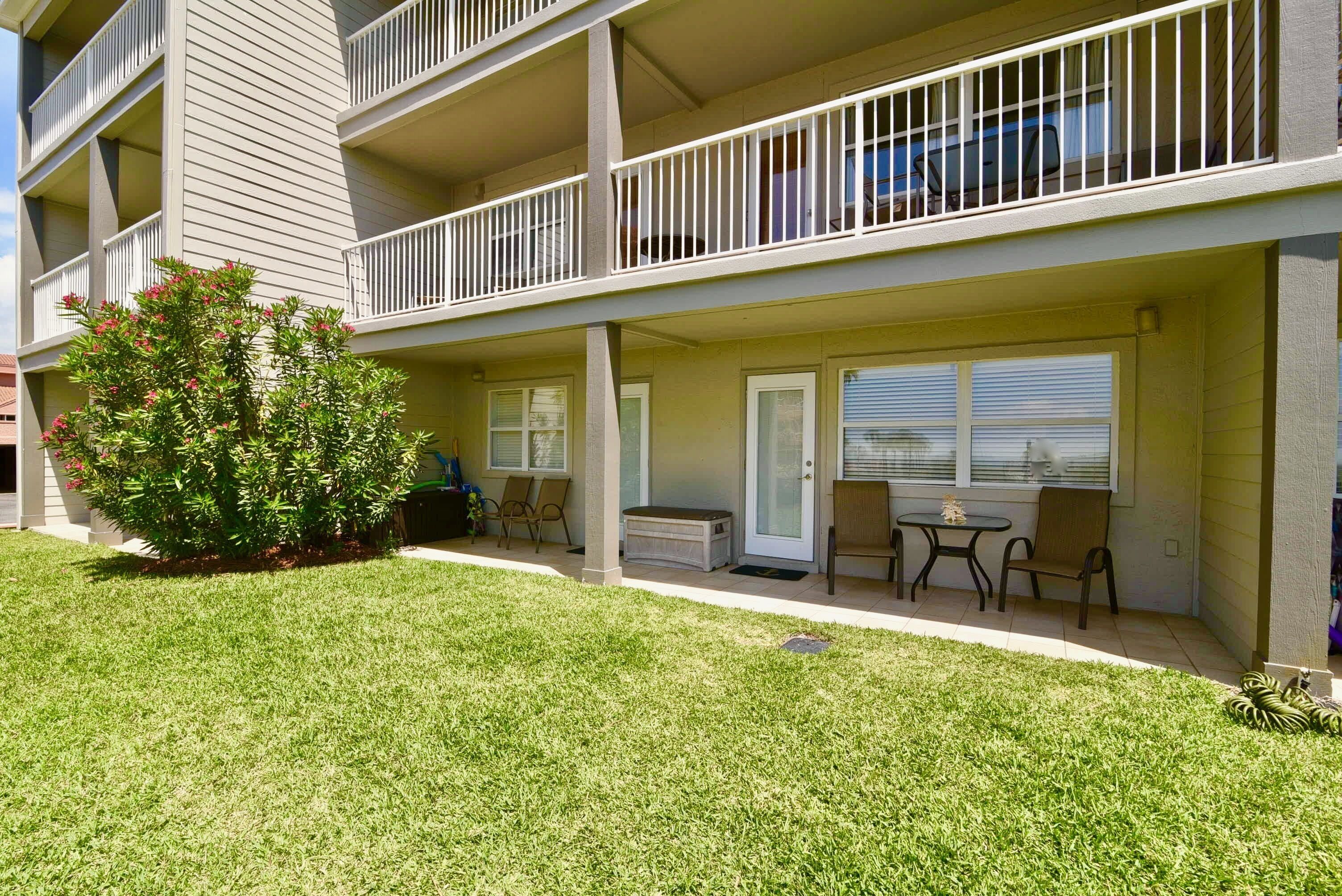 A multi-story building with a covered outdoor seating area, a small garden, and a door leading to a balcony.