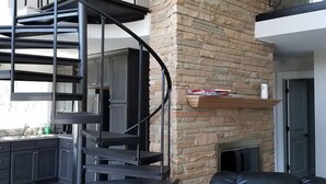 Un intérieur moderne avec un escalier en colimaçon, une cheminée en pierre et un canapé en cuir.