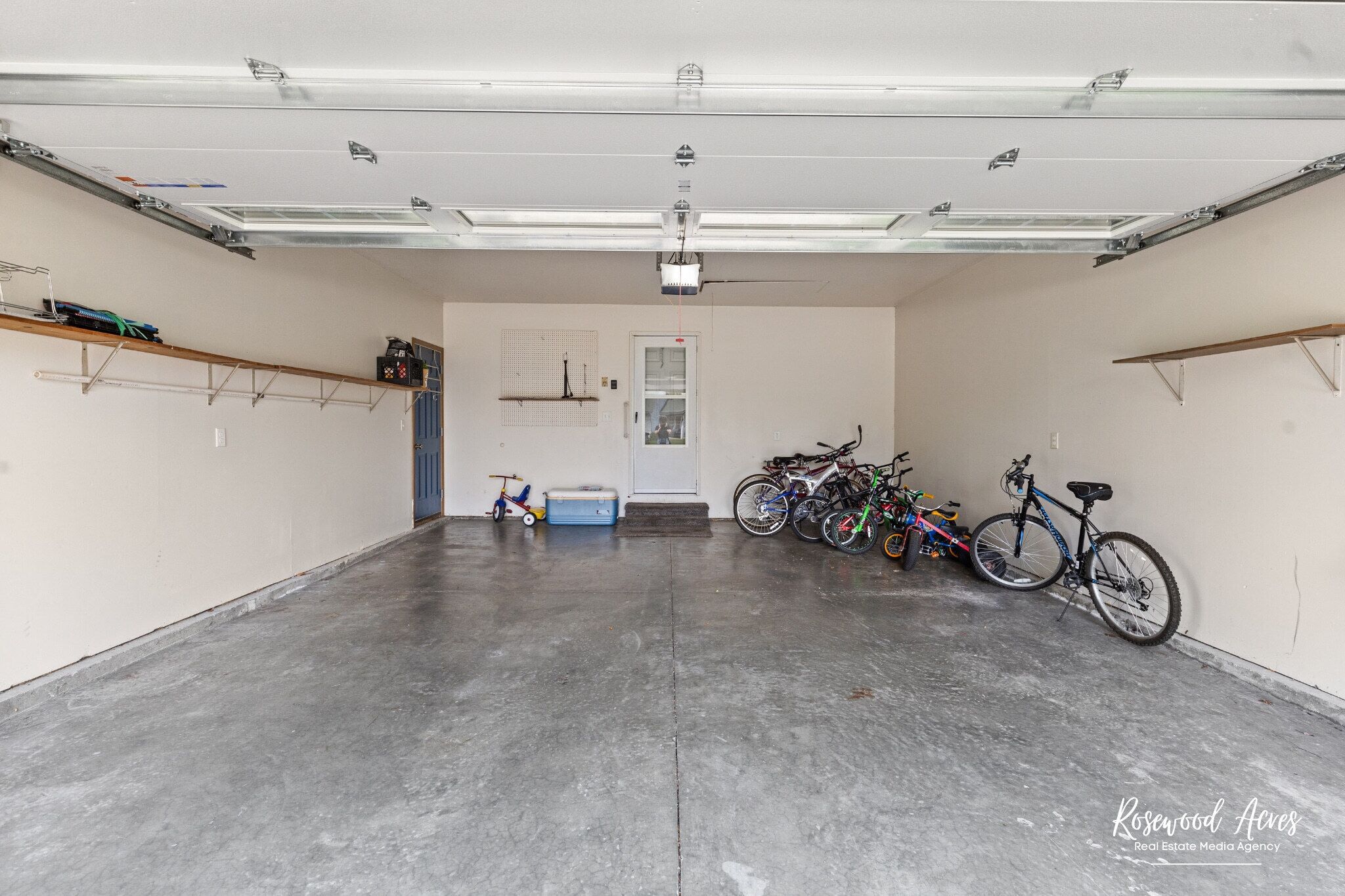 Eine geräumige Garage mit Betonboden, einem an der Decke befestigten Projektor und Fahrrädern, die an den Wänden lehnen.