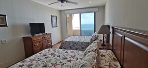 A hotel room with a bed, a TV, a dresser, and a balcony with a view of the sea. - Bella Sirena 3 room Penthouse with Amazing views (Puerto Peñasco)