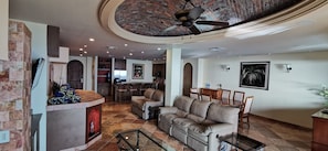 A spacious living room with a fireplace, a leather sofa, and a dining area. - Bella Sirena 3 room Penthouse with Amazing views (Puerto Peñasco)