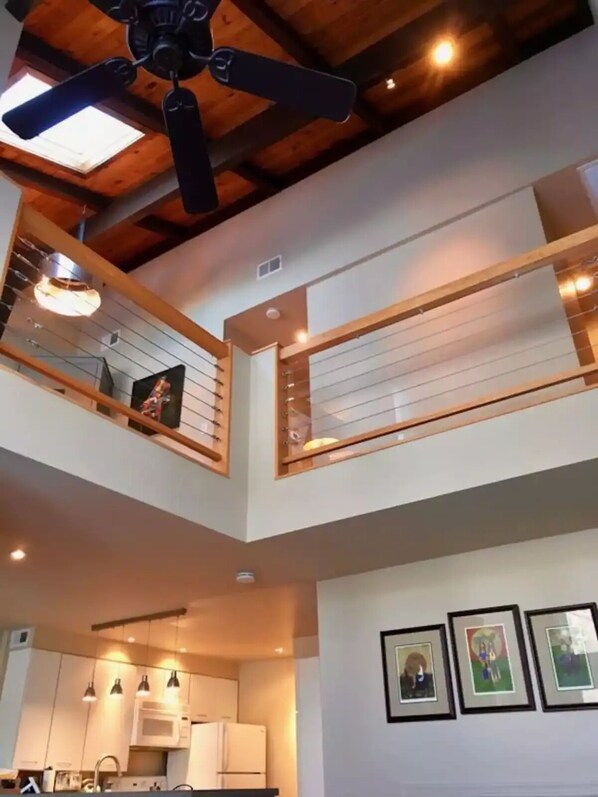 A modern interior with a kitchen, dining area, and a balcony with wooden railings.