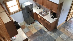 Cocina compacta con refrigerador, pileta y muebles de madera.