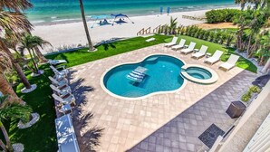 A pool area with two pools, lounge chairs, and a view of the beach. - Ocean Sands 4BR Beachfront Home in Indian Rocks (Indian Rocks Beach)