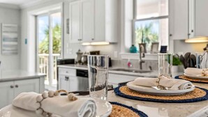 A modern kitchen with white cabinets, a marble countertop, and a view of greenery outside. - Ocean Sands 4BR Beachfront Home in Indian Rocks (Indian Rocks Beach)