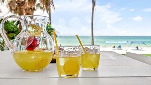 A glass pitcher and two glasses of a yellow beverage with lemon slices, placed on a table with a beach view in the background. - Ocean Sands 4BR Beachfront Home in Indian Rocks (Indian Rocks Beach)