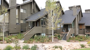 A modern multi-story building with a sloped roof, multiple balconies, and a landscaped front yard with rocks and plants. - 4 BR/4 BA Townhome - Spacious, comfortable, the perfect getaway! (Park City)