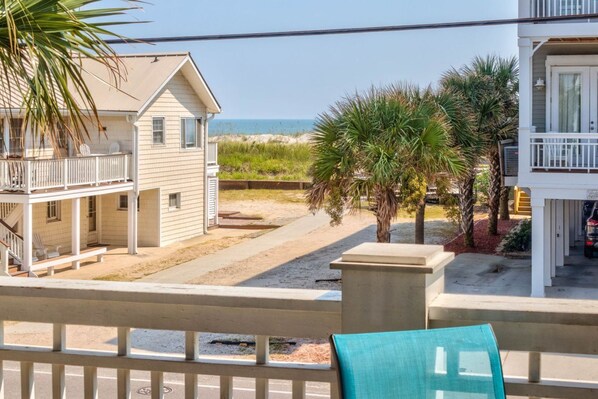 A beachfront property with a two-story house, a covered porch, and a view of the ocean.