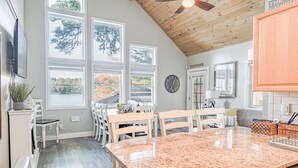 A kitchen with a granite countertop, wooden ceiling, and large windows offering views of trees. - Lakeside Retreat- Family and Pet Friendly  (Fort Ann)