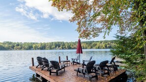 A wooden dock with chairs and a table, overlooking a calm lake with trees in the background. - Lakeside Retreat- Family and Pet Friendly  (Fort Ann)