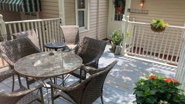 Een overdekt terras met rieten meubels, een ronde tafel en hangplanten.