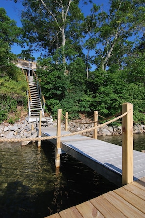Guests can access a scenic dock with a staircase leading to a raised platform amidst lush green surroundings.