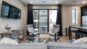 Una sala de estar moderna con un televisor de pantalla plana, dos sillones, una mesa de centro y un sofá.