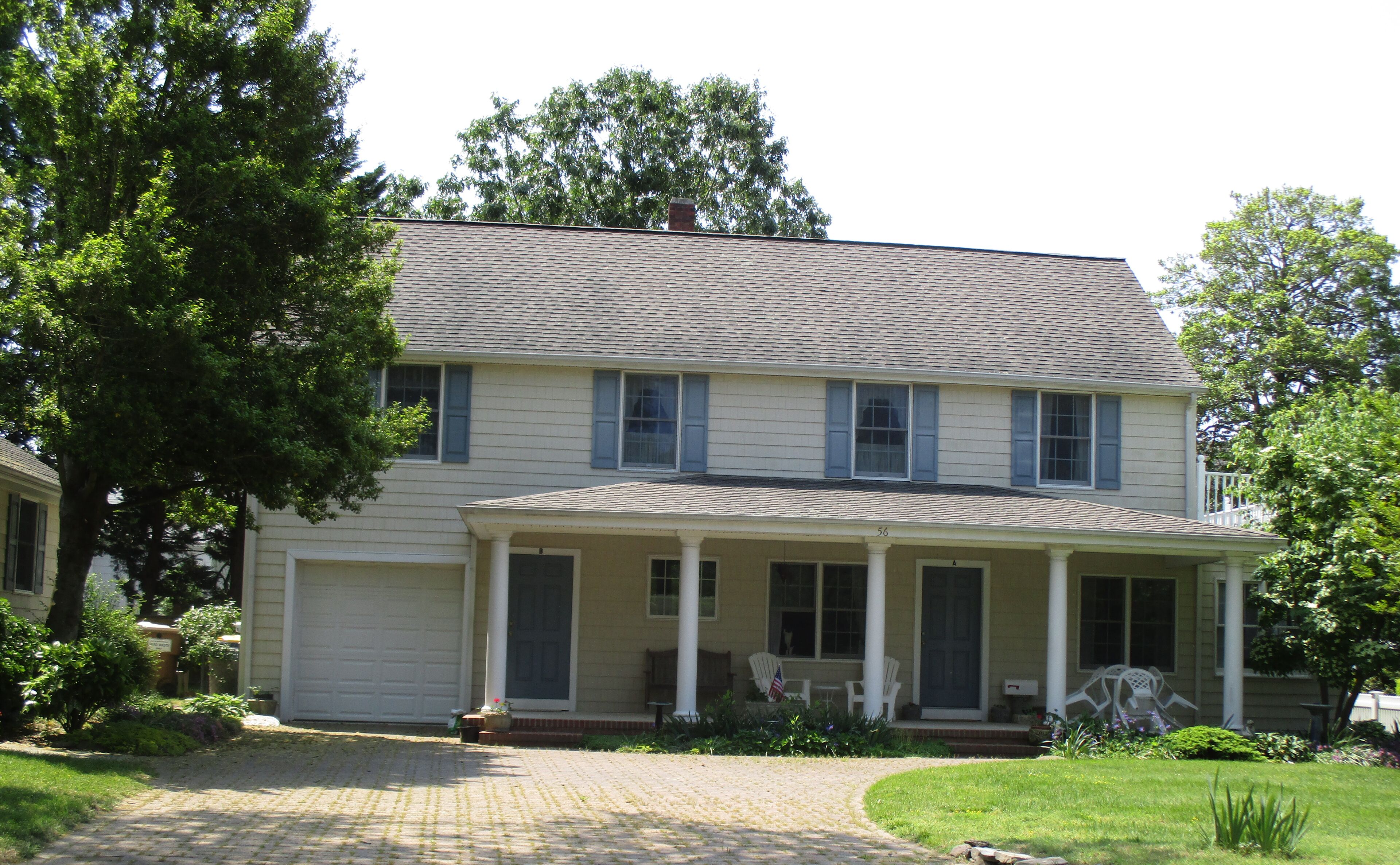 A two-story house with a covered porch, a garage, and a well-maintained lawn.