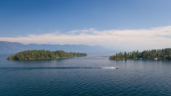 Un lago tranquilo con dos islas, una cubierta de bosque denso y la otra con árboles dispersos.