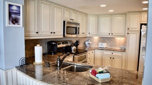 A kitchen with white cabinets, a stainless steel microwave, a granite countertop, and a sink. - 3BR/2BA Oceanfront- Gorgeous Southern View-Gorgeous Kitchen & Baths-Book Early! (Myrtle Beach)