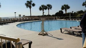 A swimming pool with lounge chairs and palm trees. - 3BR/2BA Oceanfront- Gorgeous Southern View-Great Kitchen & Baths-Book Early! (Myrtle Beach)