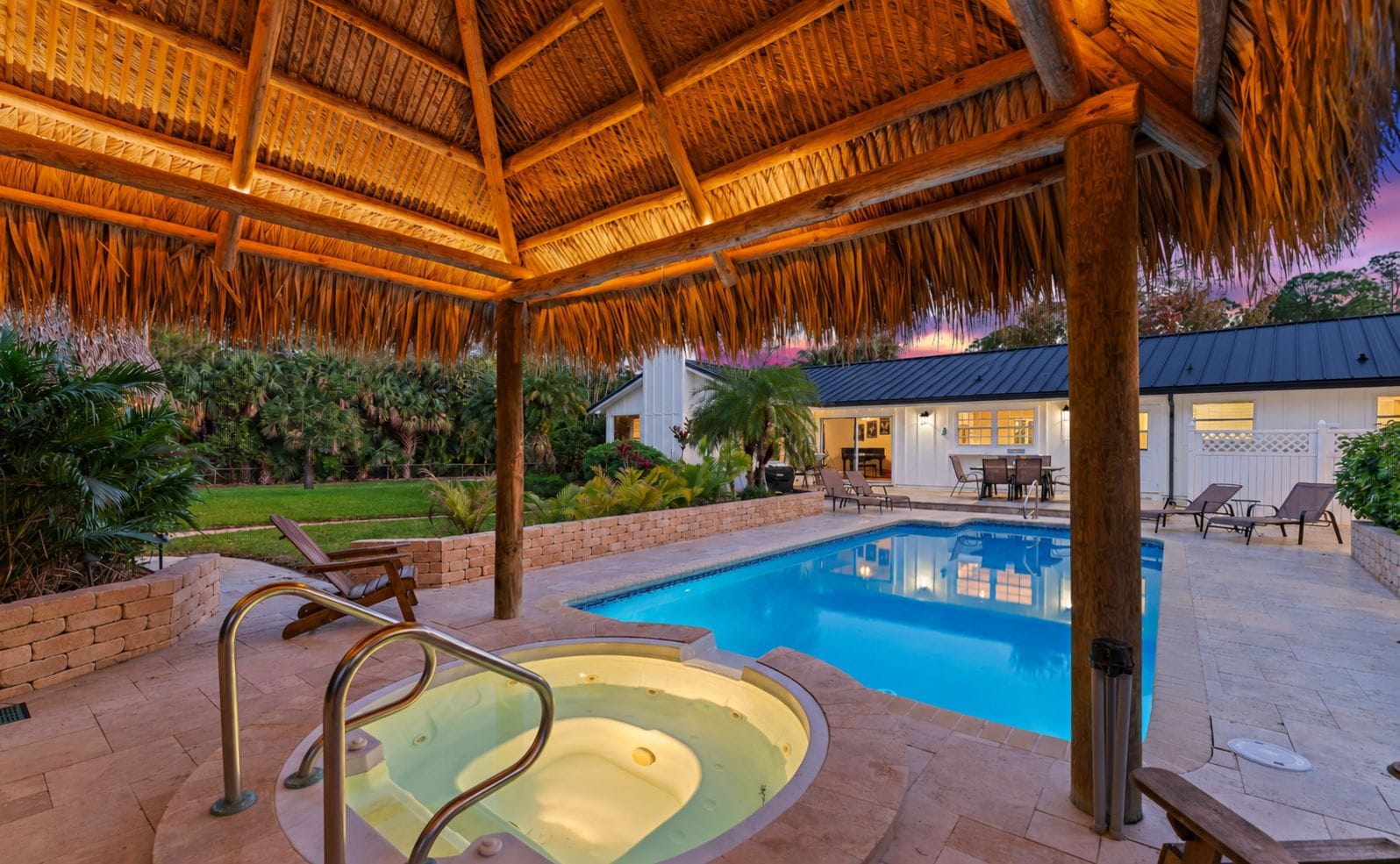 Una piscina con hidromasaje, rodeada de sillas de descanso y un área de terraza cubierta.