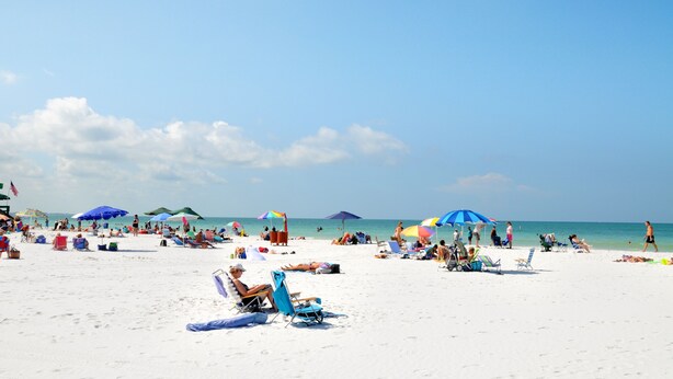 A beach with people sunbathing, umbrellas, and beach chairs. - Stunning Sunset Views-Steps to Siesta Key Beach-A Couples' Romantic Beach Condo (Siesta Key)