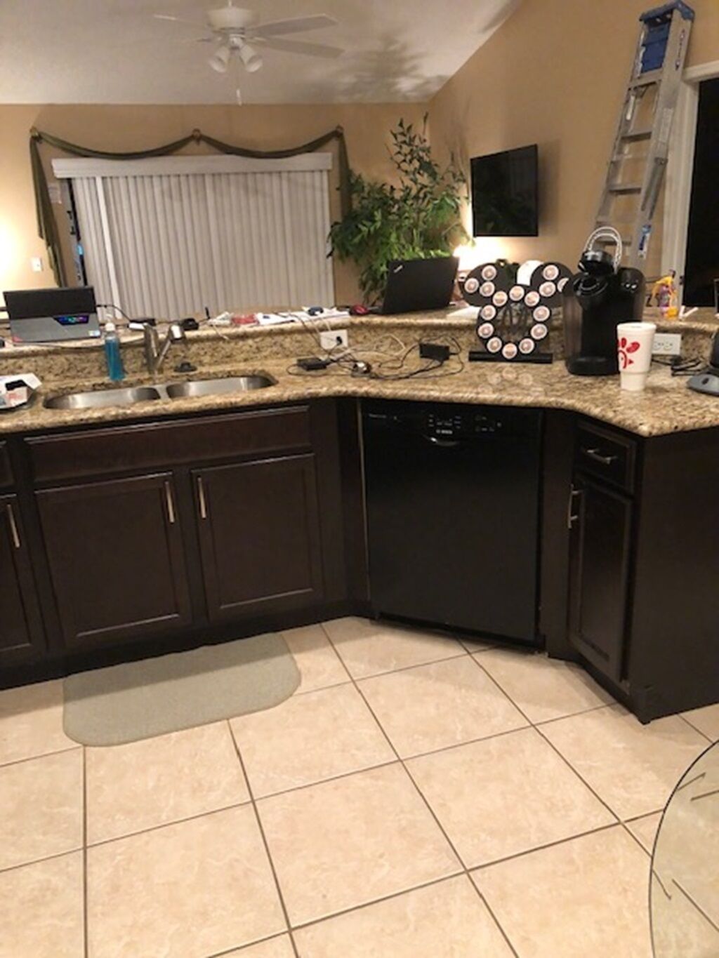 A kitchen with dark cabinets, a granite countertop, a dishwasher, and a coffee maker.