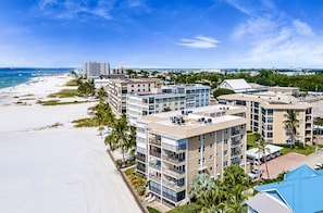 A beachfront hotel with multiple buildings, balconies, and a sandy beach.