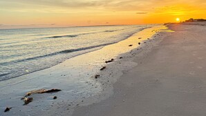 A beach with a sunset, calm water, and footprints in the sand. - On the Sand! Beachfront Pool & Views! Walk to Everything! (Fort Myers Beach)