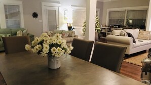 Ein Essbereich mit Holztisch, Stühlen und einer Vase mit weißen Blumen.