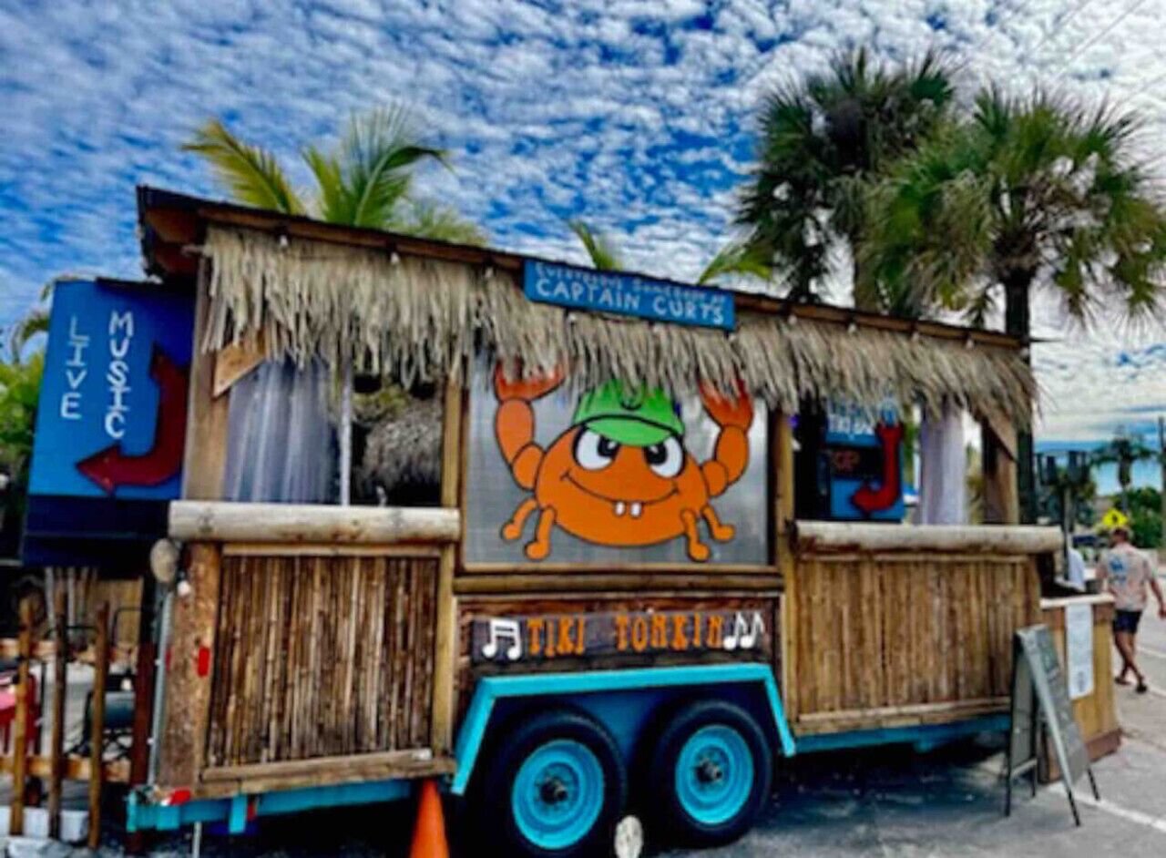 Un camión de comida con un personaje de caricatura en la carrocería, un letrero que dice "Captain Curts" y una pizarra de menú.
