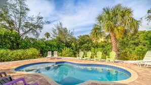 A swimming pool with a tiled edge, surrounded by greenery and palm trees.