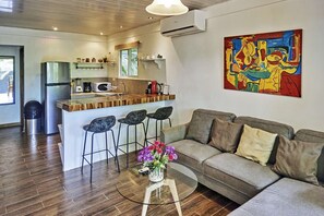 A modern living room with a grey sofa, a glass coffee table, and a colorful abstract painting.