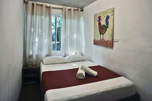 Une chambre  à coucher avec un lit, des rideaux blancs, une fenêtre et un tableau accroché au mur.