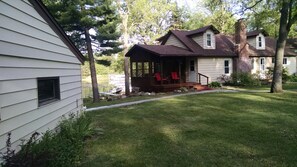 A two-story house with a covered porch and red chairs. - Getaway on BEAUTIFUL Balsam Lake, WI (Balsam Lake)