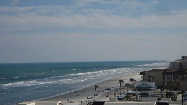A beach with a view of the ocean and a building with a sloped roof. - It’s Beachy Keen!         (New Smyrna Beach)