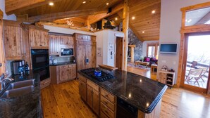 Une cuisine spacieuse avec des meubles en bois, un îlot central et un mur d’accent en pierre.