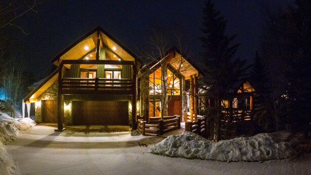 Un chalet doté d’un grand garage, d’un porche abrité et d’une allée recouverte de neige.