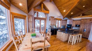 Une cuisine spacieuse dotée de meubles en bois, d’un îlot central et d’un coin repas avec une table et des chaises.