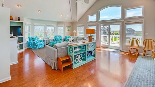 Ein geräumiges Wohnzimmer mit hohen Decken, großen Fenstern und Meerblick.