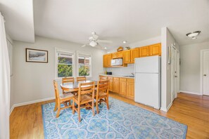 A kitchen with wooden cabinets, a white refrigerator, and a dining area with a table and chairs. - Semi-Oceanfront Home w/ Private Pool, Hot Tub, Game Room, Community Tennis (Waves)