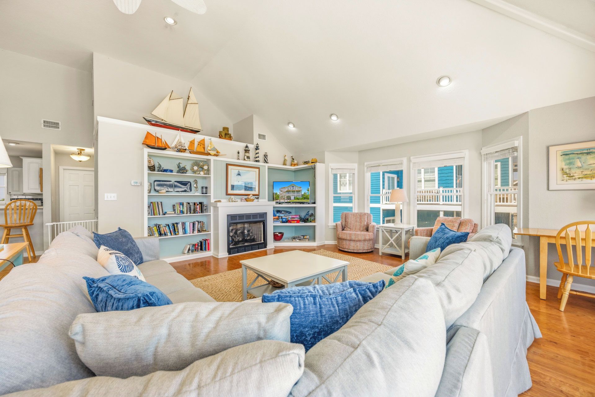A spacious living room with a large sofa, a fireplace, and a bookshelf filled with books and decorative items.