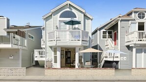 Une maison de plage à deux étages, dotée d’un balcon, d’une terrasse couverte et d’un garage.